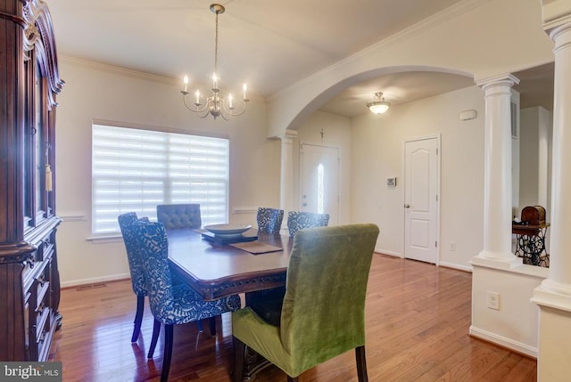 dining area featuring arched walkways, crown molding, baseboards, and wood finished floors