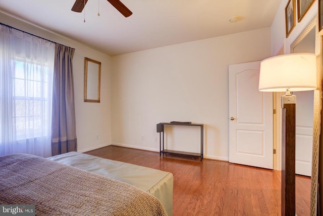 bedroom featuring baseboards, wood finished floors, and a ceiling fan