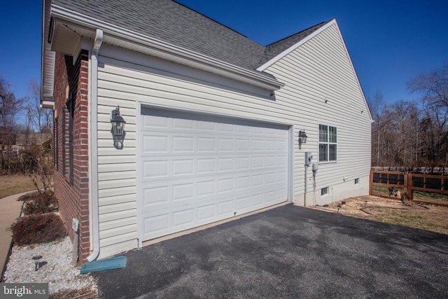 view of home's exterior featuring fence, a garage, driveway, and roof with shingles