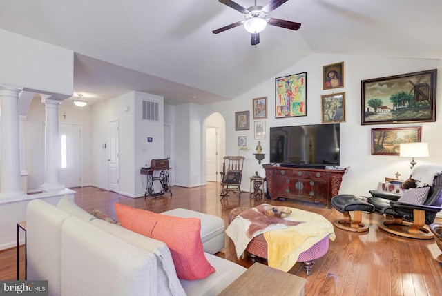 living area with lofted ceiling, wood finished floors, arched walkways, a ceiling fan, and ornate columns