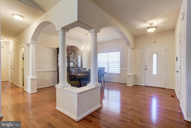 entrance foyer featuring arched walkways, visible vents, baseboards, and wood finished floors