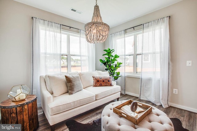 living area featuring an inviting chandelier, visible vents, baseboards, and wood finished floors