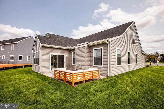 rear view of house featuring roof with shingles and a lawn