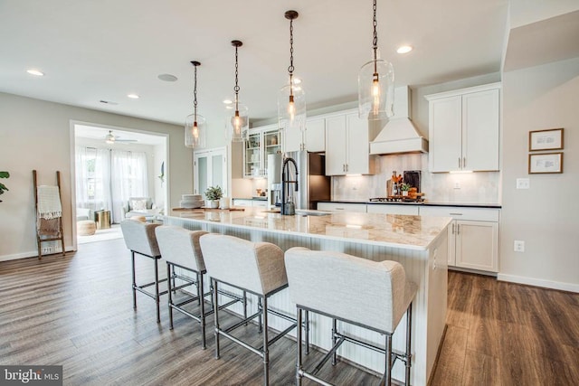 kitchen with a sink, appliances with stainless steel finishes, a large island, custom exhaust hood, and tasteful backsplash