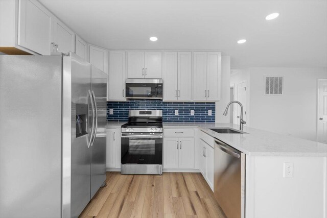 kitchen with white cabinetry, appliances with stainless steel finishes, sink, and kitchen peninsula