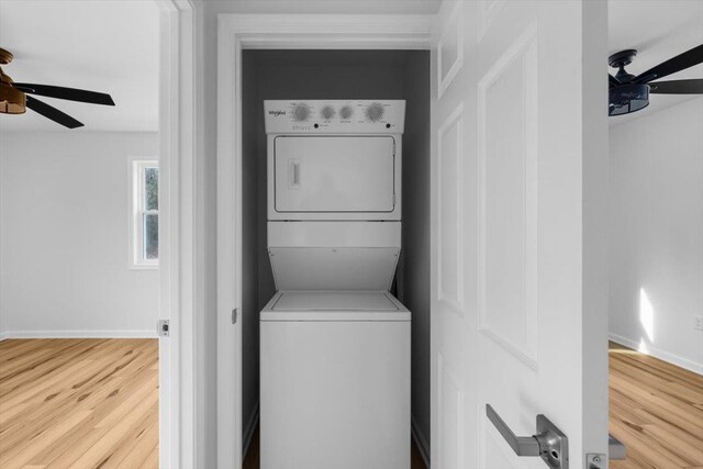 washroom with wood-type flooring, ceiling fan, and stacked washer / dryer