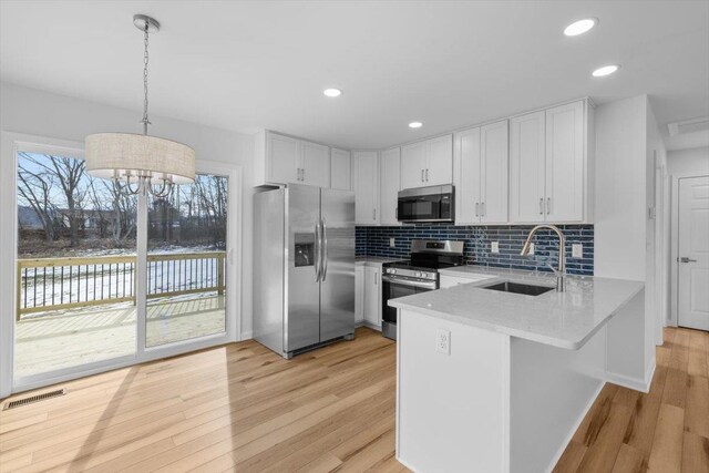 kitchen featuring sink, white cabinets, hanging light fixtures, kitchen peninsula, and stainless steel appliances