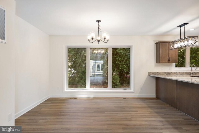 unfurnished dining area with dark hardwood / wood-style flooring, a notable chandelier, and sink