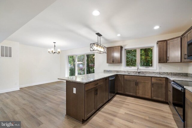 kitchen featuring sink, electric range, light stone counters, decorative light fixtures, and kitchen peninsula