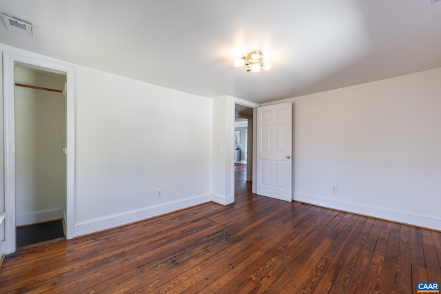 unfurnished bedroom featuring hardwood / wood-style floors, baseboards, and visible vents