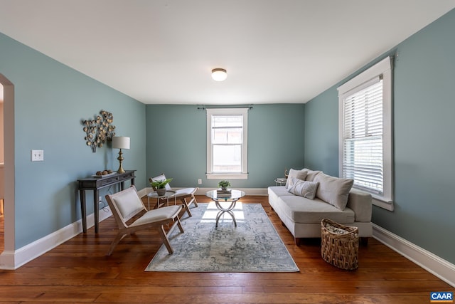 living room featuring baseboards, arched walkways, and wood finished floors