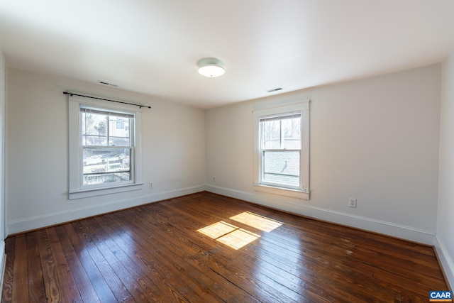 spare room with baseboards, a healthy amount of sunlight, and hardwood / wood-style floors