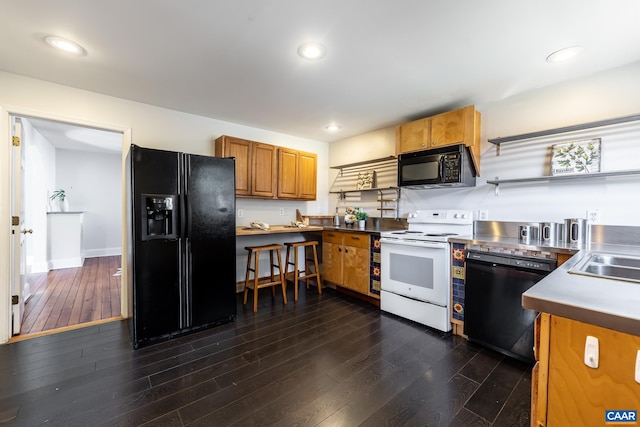 kitchen with brown cabinetry, stainless steel counters, recessed lighting, dark wood-style floors, and black appliances