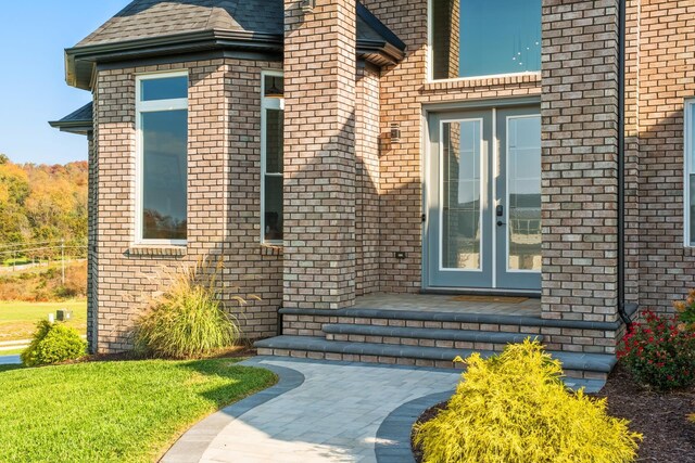 view of exterior entry with french doors and a lawn