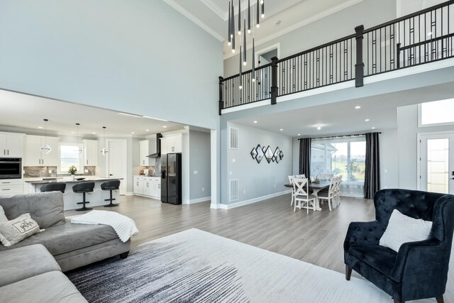 living room with crown molding, light hardwood / wood-style floors, and a high ceiling