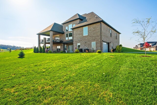 back of house with a yard, a garage, and a balcony