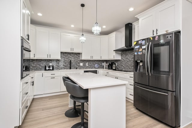 kitchen featuring white cabinetry, wall chimney range hood, a kitchen island, and black appliances