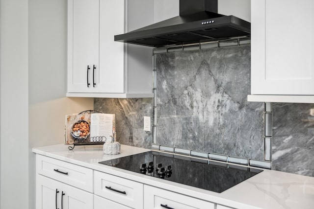 kitchen with white cabinets, black electric stovetop, and wall chimney range hood