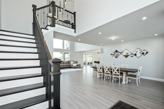 dining space featuring wood-type flooring and a high ceiling