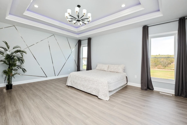 bedroom featuring crown molding, light hardwood / wood-style flooring, an inviting chandelier, and a tray ceiling