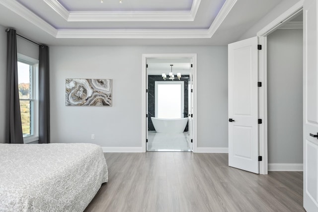 bedroom with ornamental molding, a tray ceiling, and light hardwood / wood-style floors