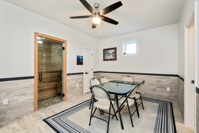 dining space featuring tile walls, ceiling fan, and light wood-type flooring