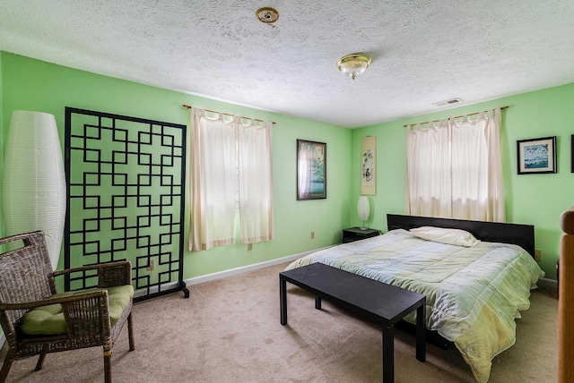 bedroom with a textured ceiling, carpet flooring, visible vents, and baseboards