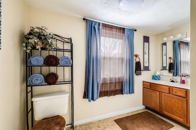 bathroom featuring toilet, baseboards, a textured ceiling, and vanity