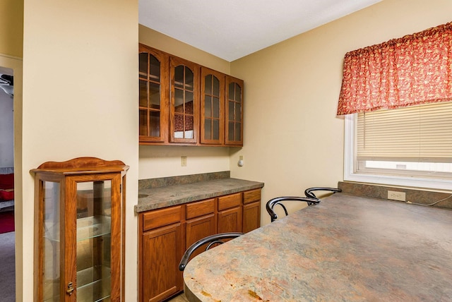 kitchen with dark countertops, glass insert cabinets, and brown cabinetry