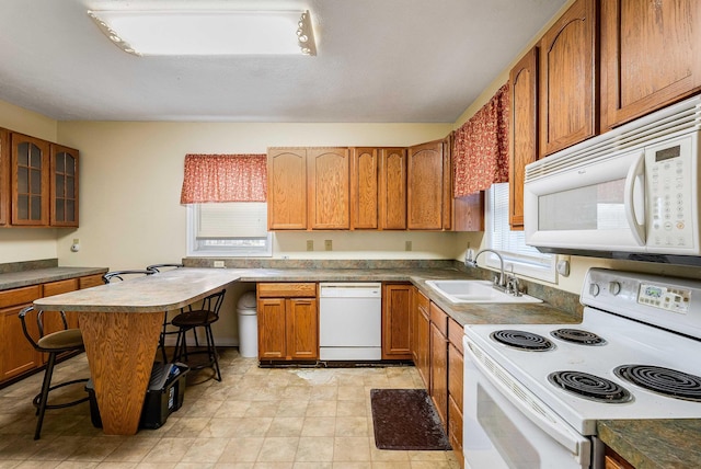 kitchen with a healthy amount of sunlight, white appliances, brown cabinets, and a sink