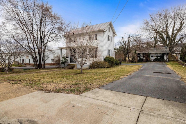 view of front of house with aphalt driveway, a front yard, metal roof, and a porch