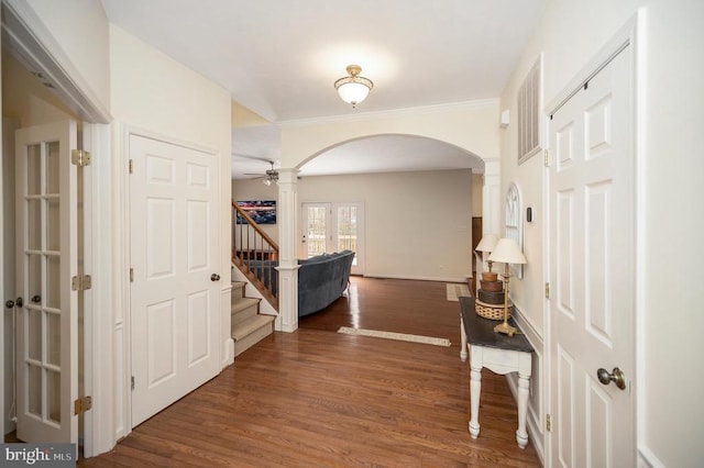 corridor with dark wood finished floors, arched walkways, stairs, and visible vents