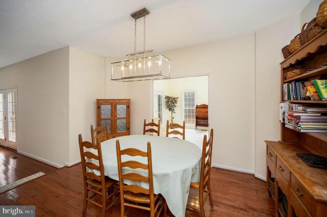 dining space featuring baseboards, a chandelier, and dark wood-type flooring