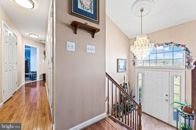 foyer entrance featuring a notable chandelier, wood-type flooring, and a high ceiling