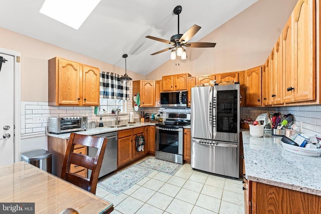 kitchen featuring sink, hanging light fixtures, light tile patterned floors, light stone counters, and stainless steel appliances