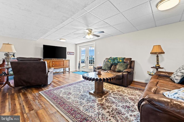 living room with french doors, ceiling fan, a drop ceiling, and hardwood / wood-style flooring