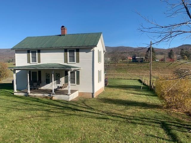 back of house with a mountain view, a lawn, and a patio