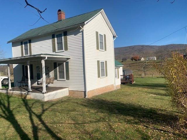 back of property featuring a mountain view and a yard