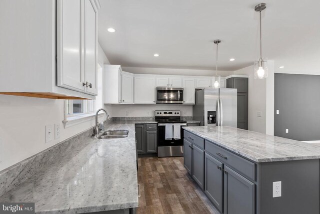 kitchen with sink, white cabinetry, hanging light fixtures, stainless steel appliances, and a center island