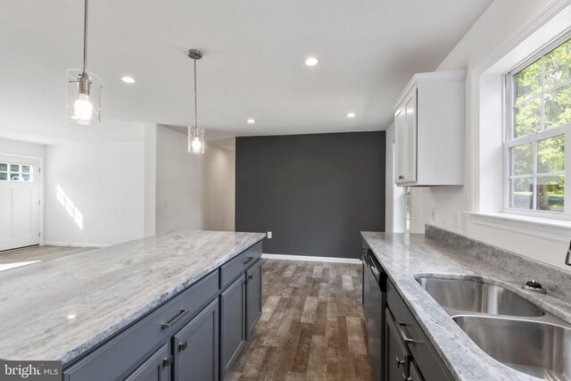 kitchen featuring white cabinetry, sink, light stone counters, and pendant lighting