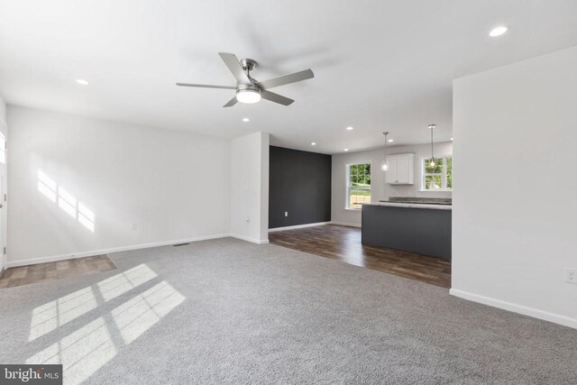 unfurnished living room with dark carpet and ceiling fan