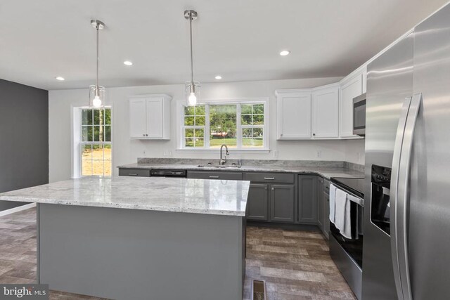 kitchen featuring sink, appliances with stainless steel finishes, hanging light fixtures, white cabinets, and a kitchen island