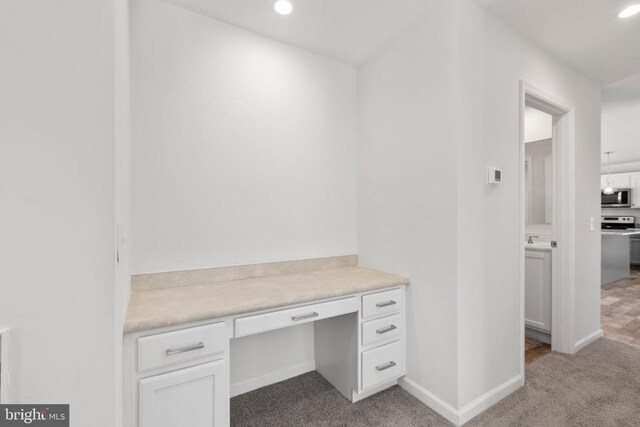 unfurnished office with light colored carpet and built in desk