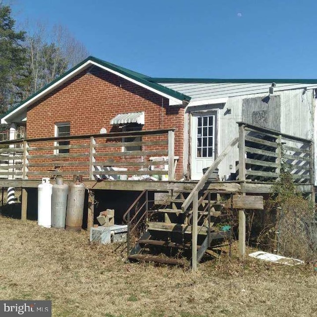 back of property featuring a deck and brick siding