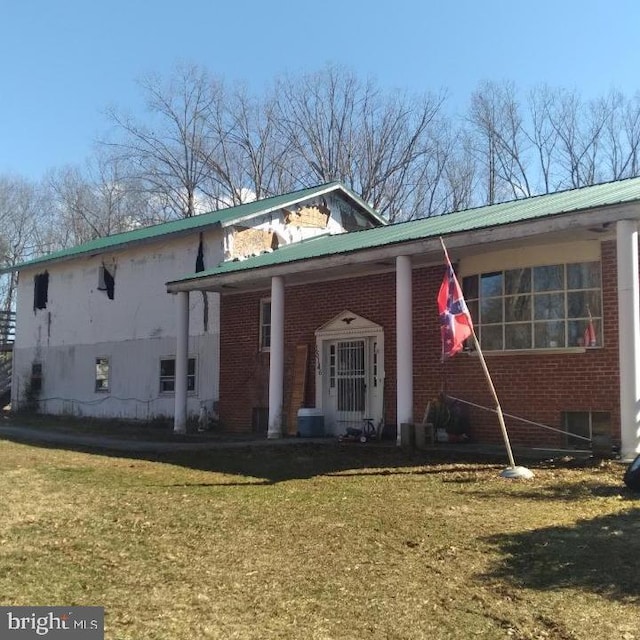 view of front of house with a front yard, brick siding, and metal roof