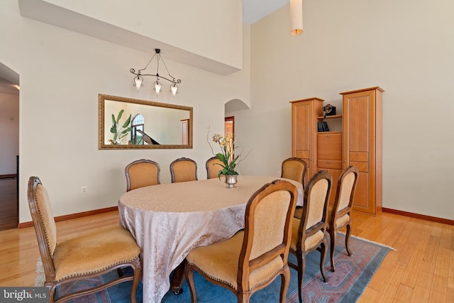 dining area featuring a towering ceiling and light hardwood / wood-style flooring