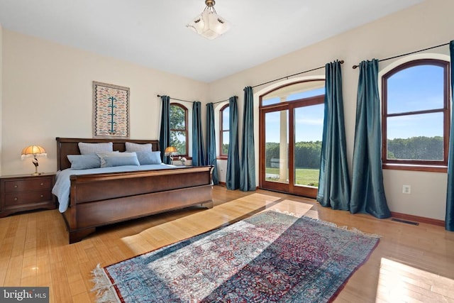 bedroom with access to exterior, multiple windows, and light hardwood / wood-style flooring