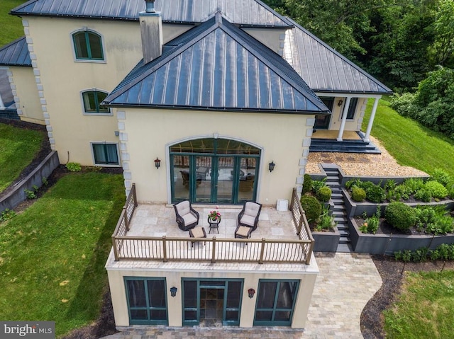 back of house with french doors, a balcony, and a yard