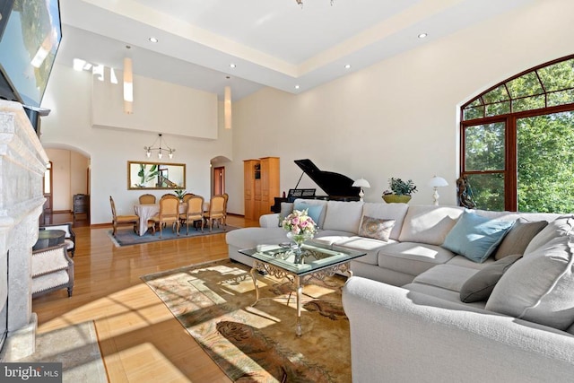 living room with a towering ceiling, hardwood / wood-style floors, and a notable chandelier