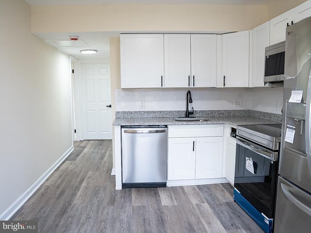 kitchen featuring stainless steel appliances, sink, white cabinets, and light hardwood / wood-style flooring